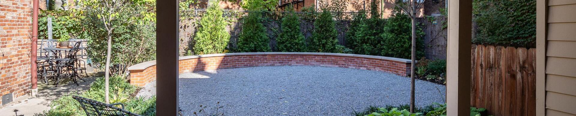 Outdoor courtyard with brick seating wall, trees, and patio area